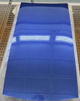 Blue structural PV prototype panel in hood-scale geometry on a drying rack